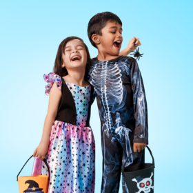 Small girl and boy dressed in Halloween costumes laughing