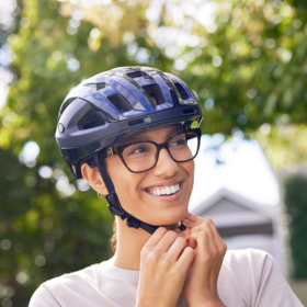 Lady smiling and clipping on a blue bicycle helmut