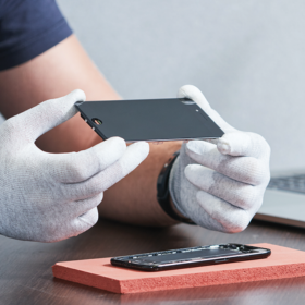 person wearing gloves repairing an iphone